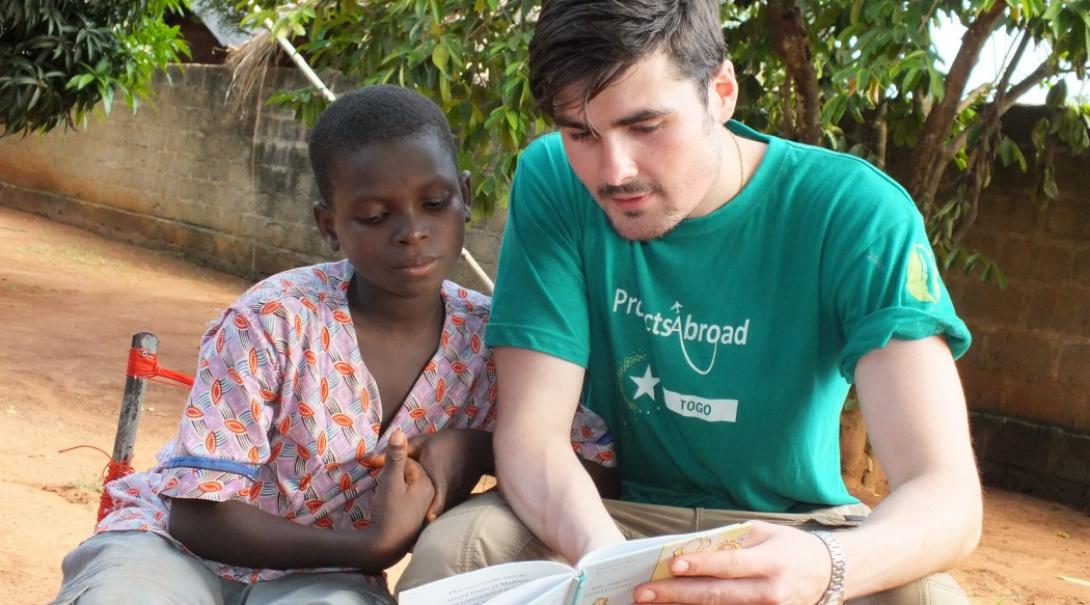 Togo volunteer helps a child read Volunteer reads with a child